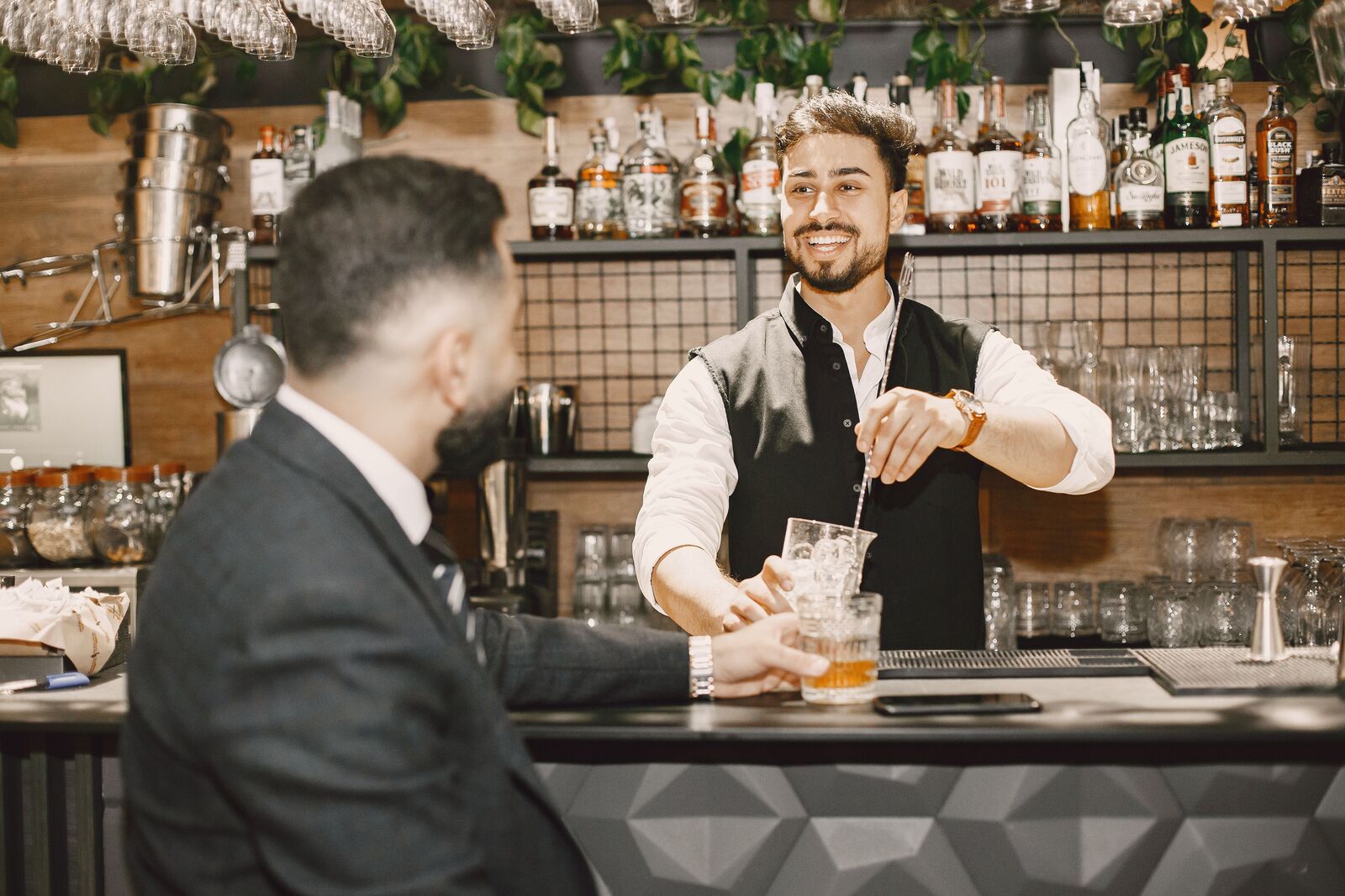Barkeeper berät einen Gast lächelnd an der Bar