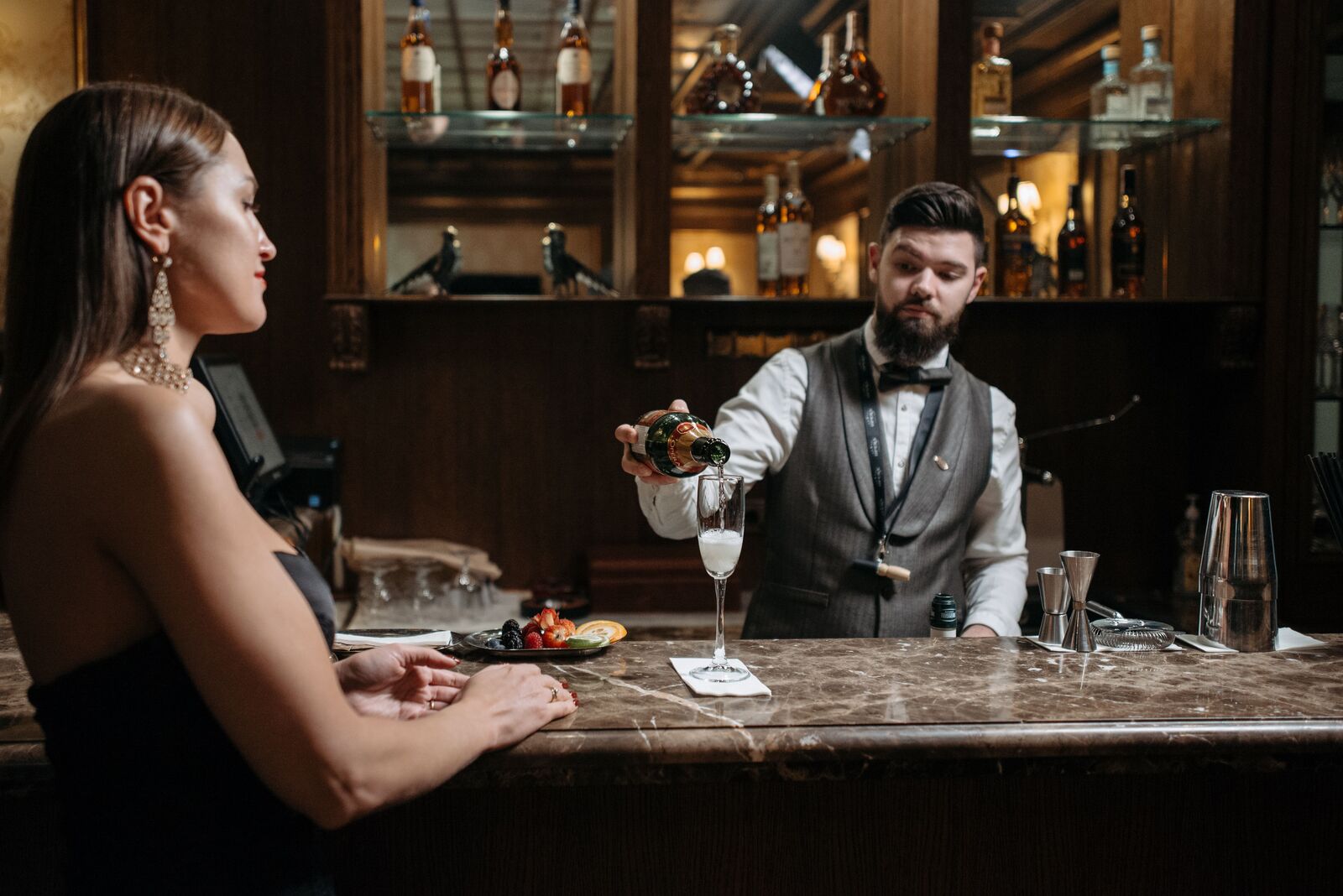 Barkeeper schenkt einer Gästin ein Glas Champagner ein