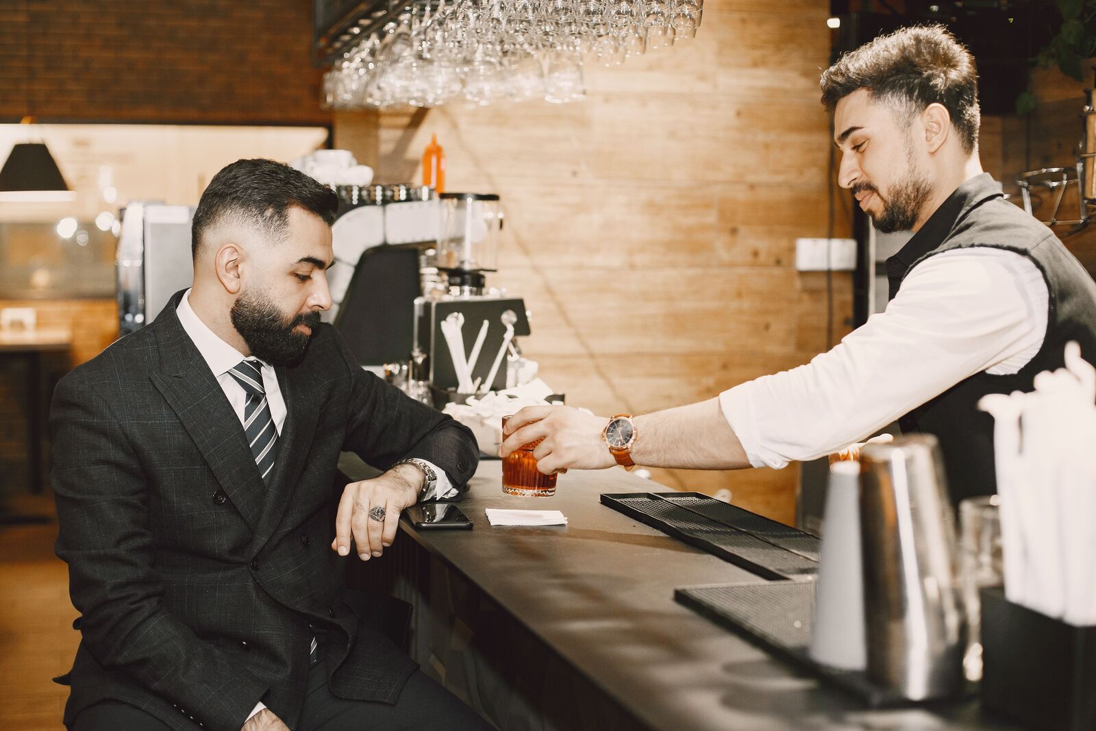 Barkeeper serviert einem Gast souverän einen Drink