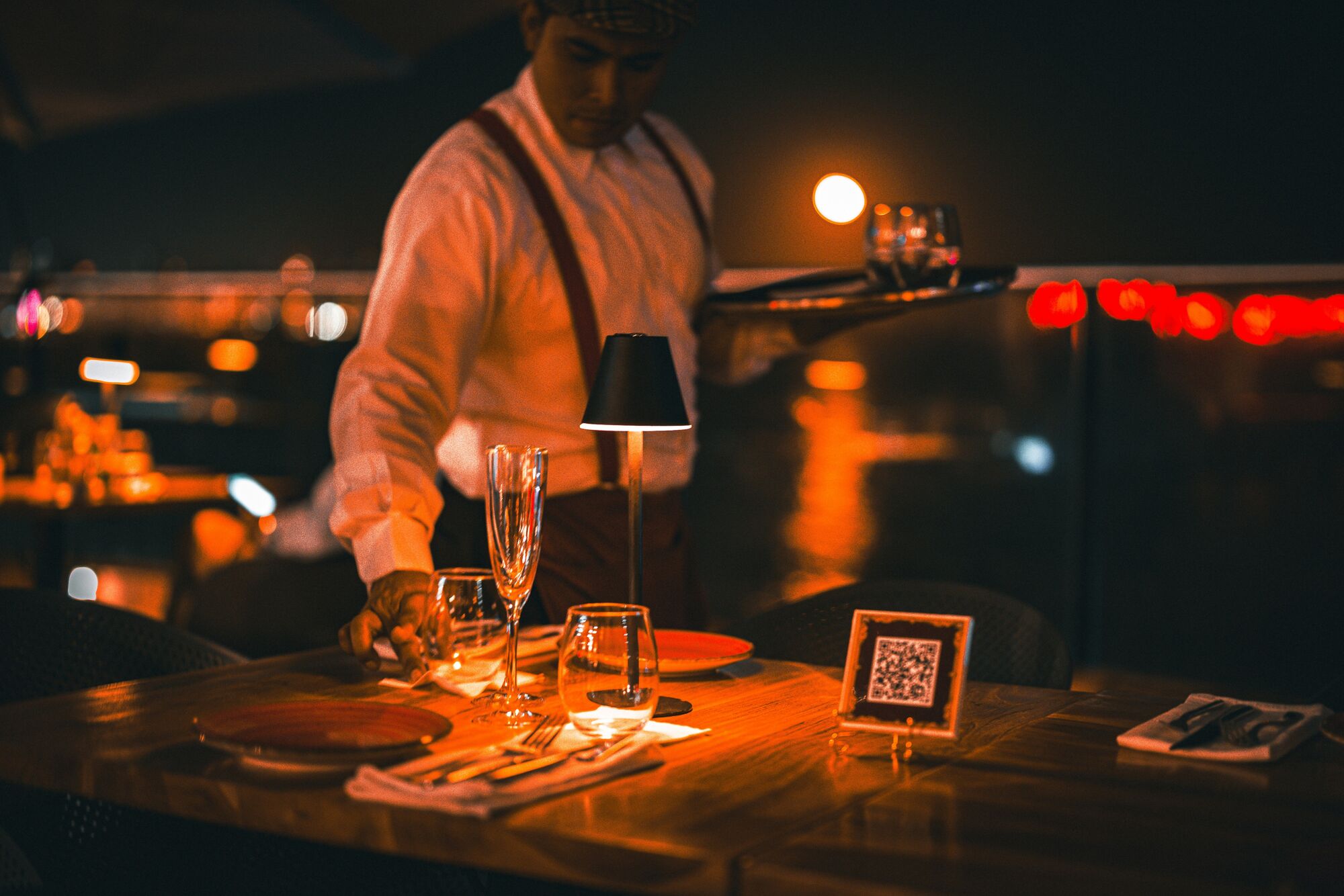 Kellner deckt am Abend einen Tisch in einem Rooftop-Restaurant ein