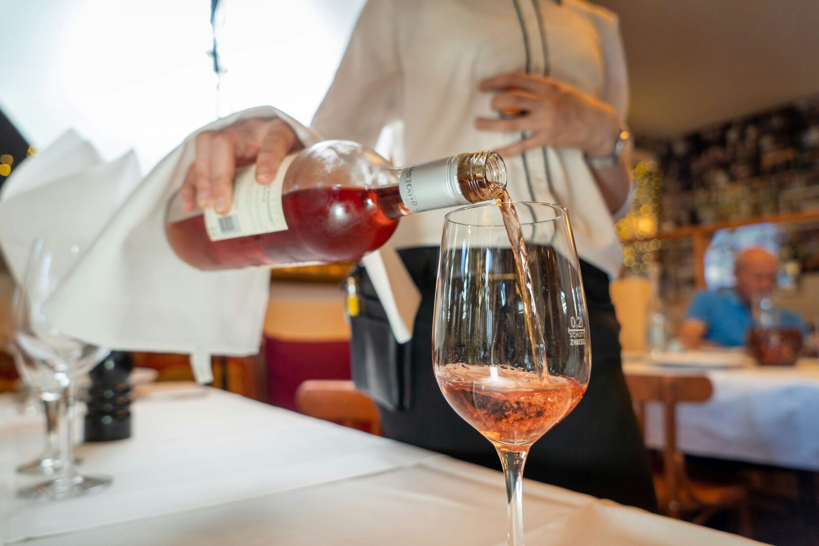 Servicekraft schenkt Roséwein professionell in ein Glas ein